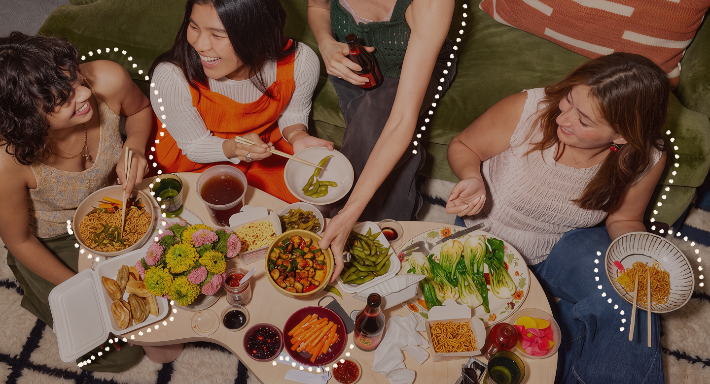 Friends sharing dishes from several restaurants around a table